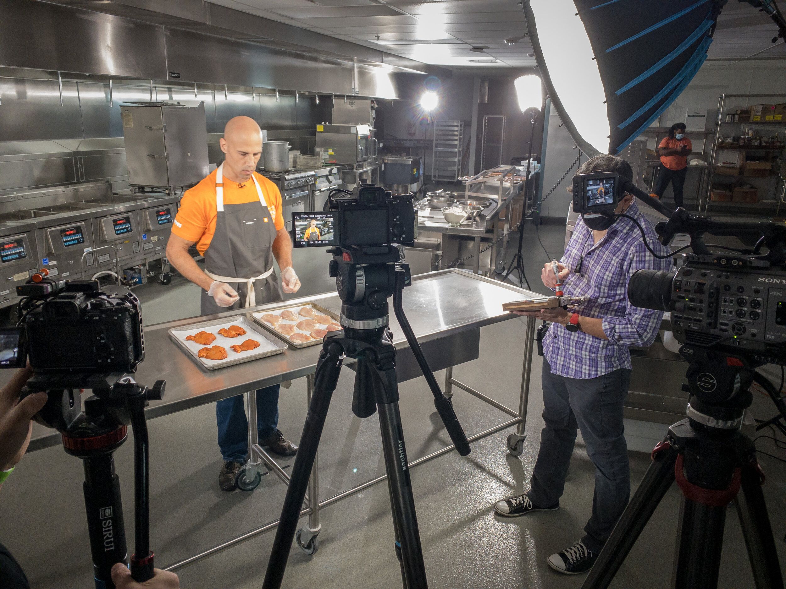 A professional camera crew filming a chef in a commercial kitchen